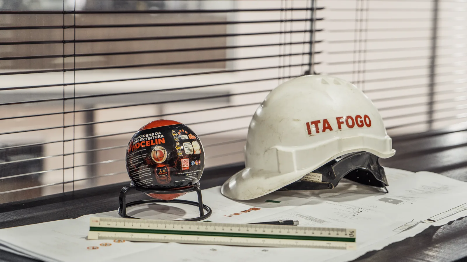 Capacete da ITA FOGO sobre planta técnica de engenharia civil